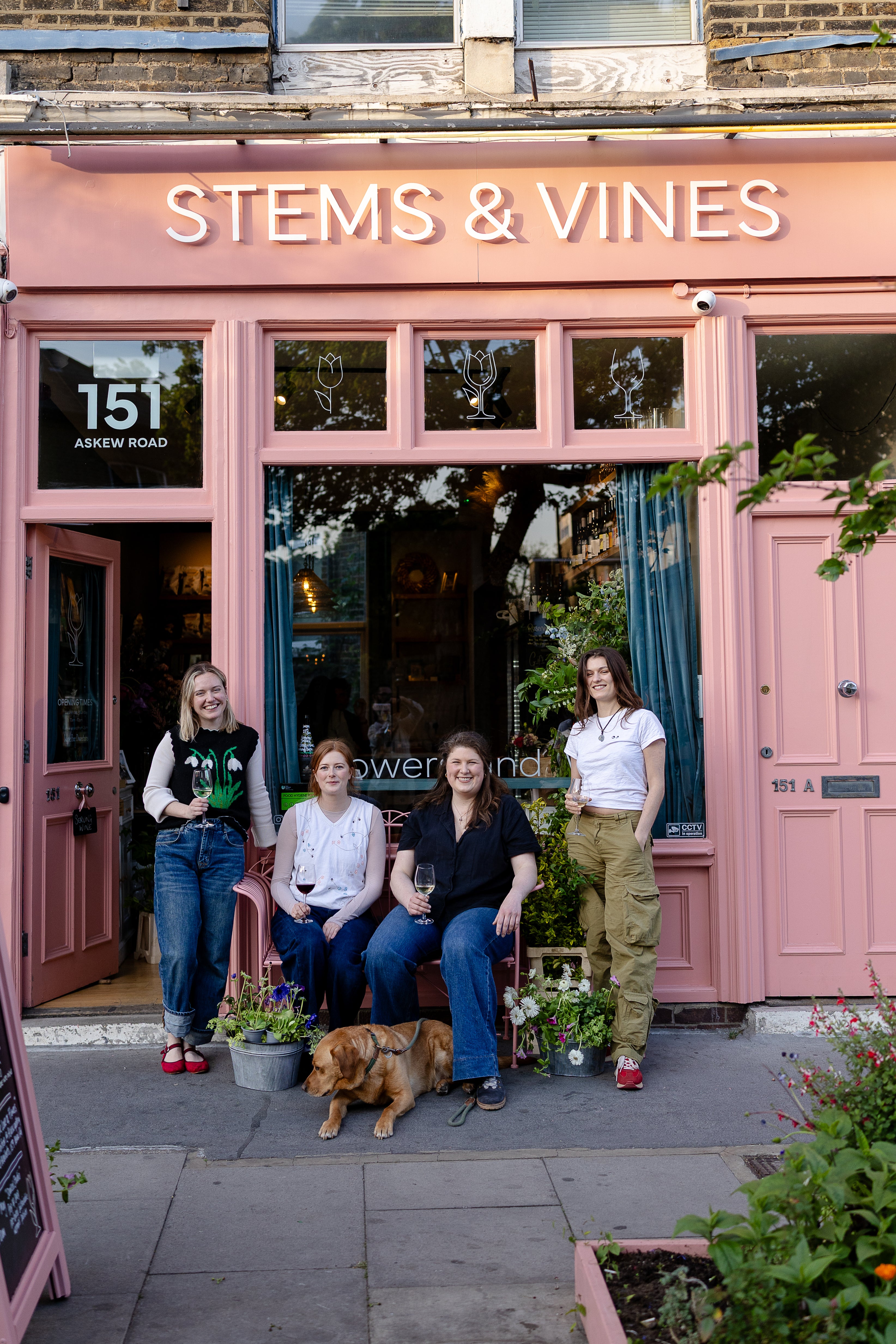 Four of the staff from Stems & Vines and Brisket the shop dog standing outside a pink building with 'Stems & Vines' sign.
